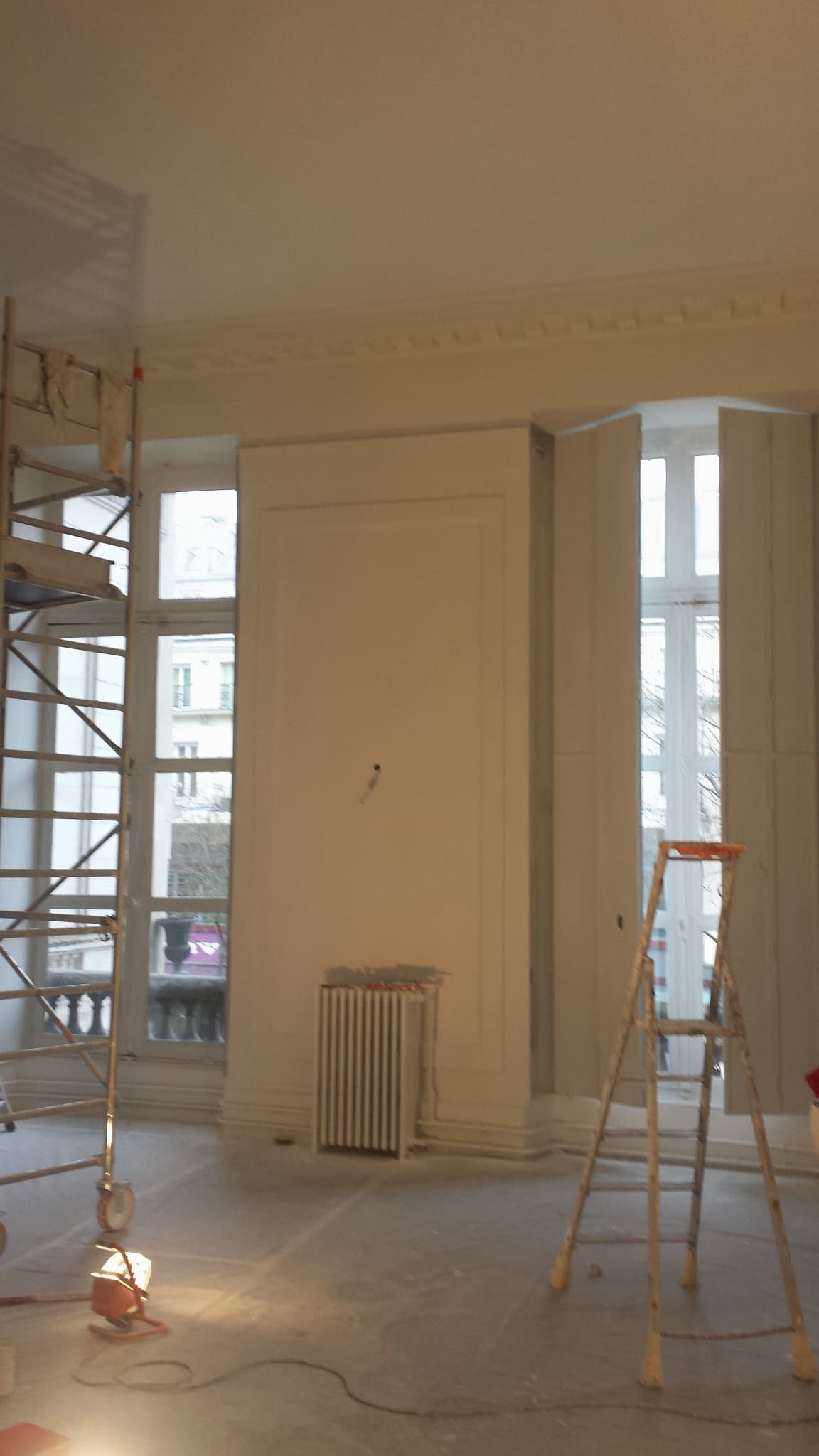 Pièce en chantier avec échafaudage, escabeau et protections de sol.