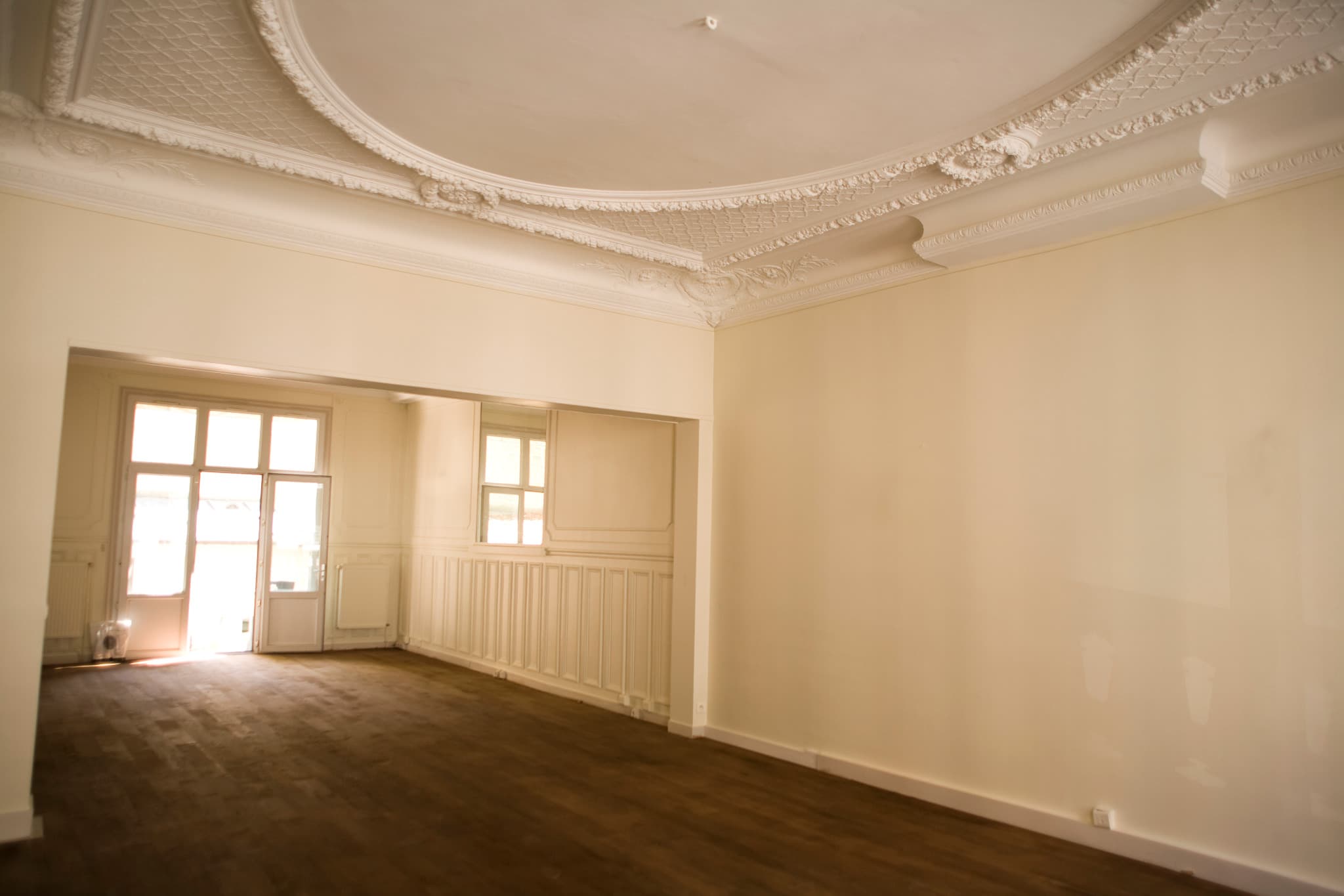 Deux pièces en enfilade, plafond orné et grandes fenêtres.