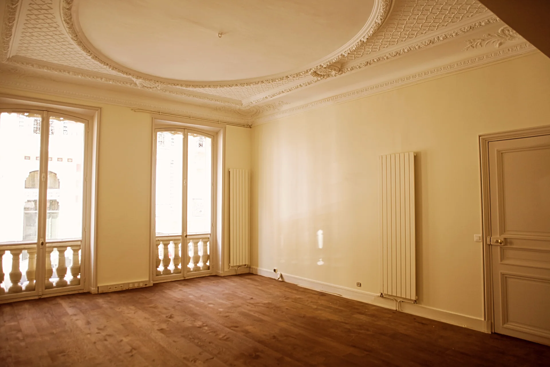 Intérieur parisien : parquet, plafond orné et grandes fenêtres.